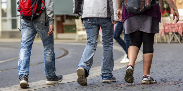 drei Menschen gehen zu Fuß auf einem Gehweg