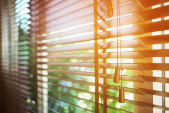 Foto: Holzjalousien mit Sonnenstrahlen © islander11/123RF geschlossene Jalousien vor einem Fenster