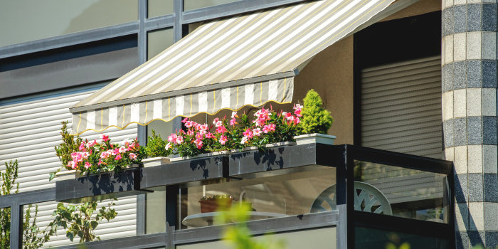 Eine geöffnete Markise über ein mit Blumen geschmückter Balkon