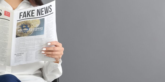 eine Frau liest eine Zeitung, auf der Titelseite steht "Fake News"