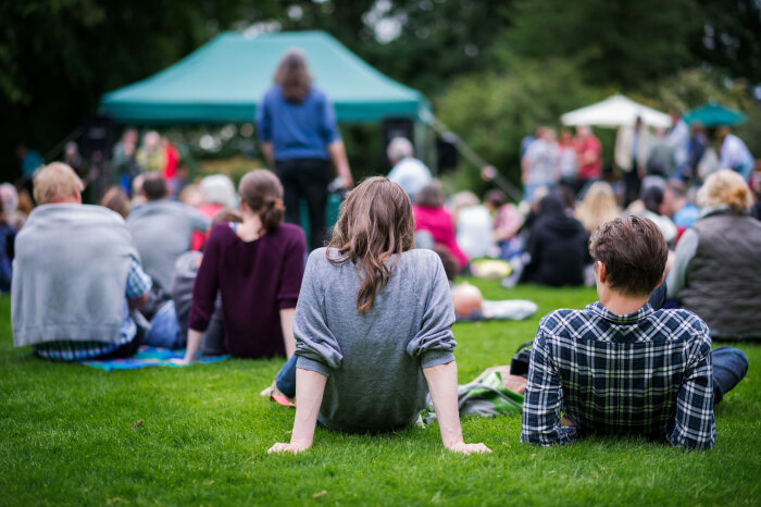 Menschen sitzen auf einer Wiese, von hinten zu sehen Menschen sitzen auf einer Wiese, von hinten zu sehen