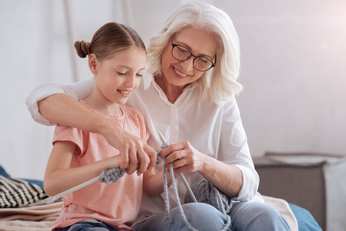 Eine ältere Frau zeigt einem Mädchen Stricken Eine ältere Frau zeigt einem Mädchen Stricken