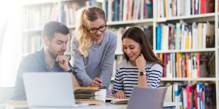 Drei Personen stehen in einer Bibliothek