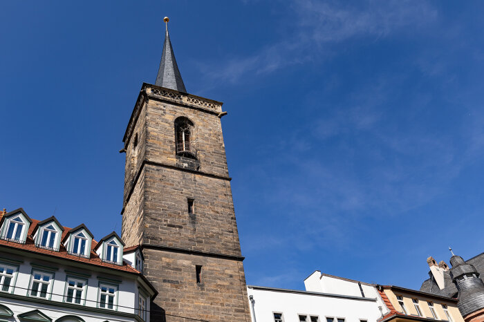 Außenansicht des Bartholomäusturms Glockenturm aus Backsteinen in einer Häuserfront bei blauem Himmel