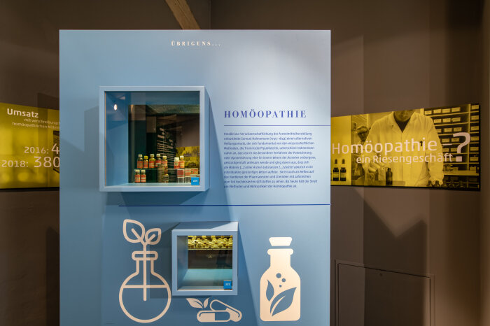 Exponatenwand in der Ausstellung Exponatenwand mit Fläschchen und Pillen