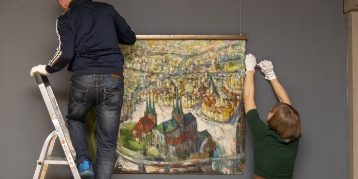 zwei Personen hängen ein Gemälde der Stadt Erfurt auf