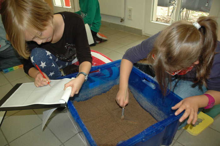 Eigene Ausgrabung im Stadtmuseum Zwei Kinder bearbeiten Erde in einer Kiste