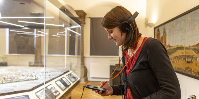 Eine Frau, die Kopfhörer trägt, scannt mit ihrem Handy einen QR-Code.