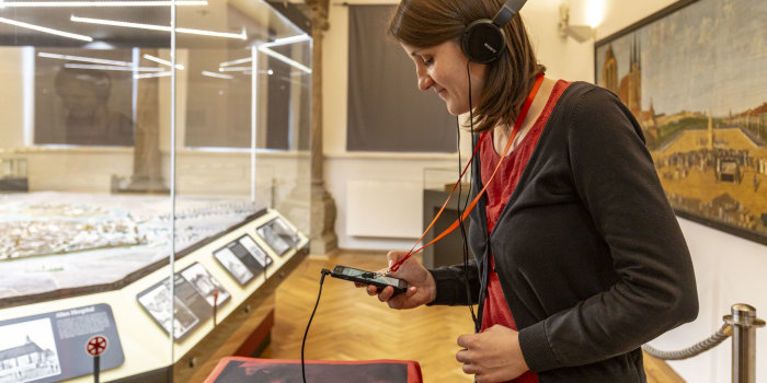 Eine Frau, die Kopfhörer auf hat, scannt mit ihrem Handy einen QR-Code