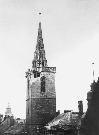 Schwarz-Weiß-Foto: Kirchturm mit Bombenschäden am Dach