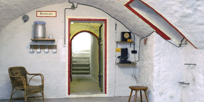Kellereingang mit Treppenstufen, davor Gewölberaum, weiß gestrichen mit Einrichtungsgegenständen