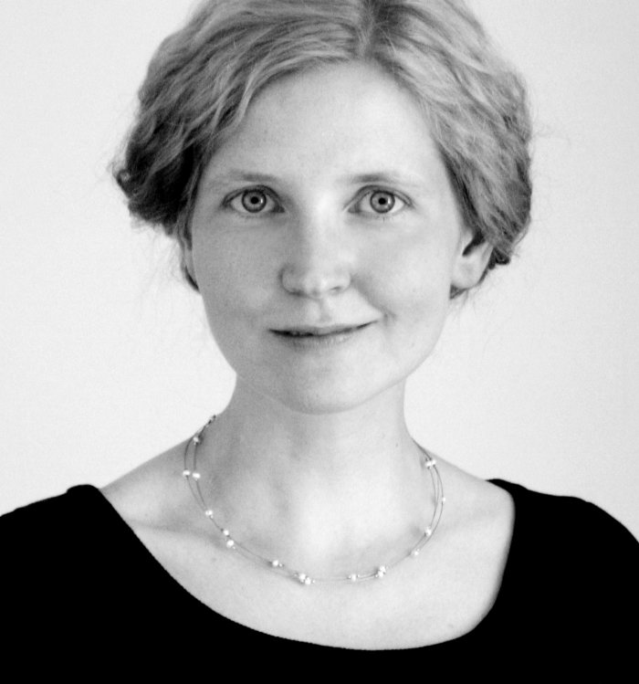 Diana Matut Klassisches Schwarz-Weiß-Porträtfoto: Eine Frau mit leicht gelockten, hinten zusammengefaßten hellen Haaren schaut gerade in die Kamera. Sie trägt eine Perlenkette und einen schwarzen Pullover.