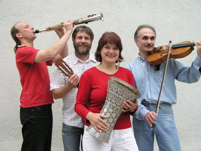 Drei Männer und eine Frau mit Musikinstrumente in den Händen, die in einer Gruppe zusammenstehen