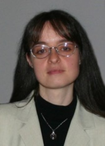 Eine Frau mit Brille und langen braunen Haaren blickt in die Kamera. 