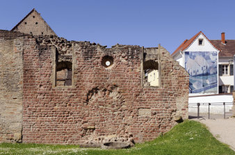 Foto: Mittelalterliche Synagoge in Speyer © Lukas Clemens Eine Backsteinmauer mit einer zugemauerten Tür, darüber zwei Rundbogenfenster mit einem runden Fenster dazwischen.