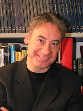 Foto: Dr. Jürgen Bärsch © Dr. Jürgen Bärsch Ein Mann in einem schwarzen Sakko steht vor einem Bücherregal und blickt in die Kamera.