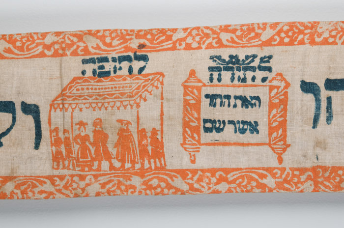 Torawimpel ein Ausschnitt aus einem Torawimpel mit orangefarbenen Bildern und schwarzer Schrift