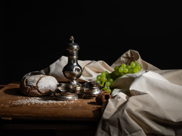 bunte Fotografie einer angerichteten Tafel mit Brot, Salz, Weintrauben und Teekanne