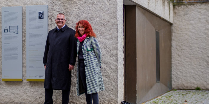 Zwei Personen stehen neben den Tafeln an der Mikwe in Erfurt.