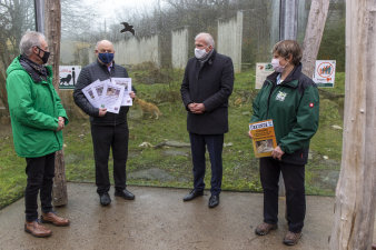 vier Personen stehen vor dem Löwengehege im Thüringer Zoopark Erfurt, zwei halten Urkunden in den Händen