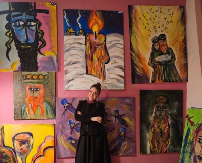 Daniela Bromberg und einige ihrer Werke Junge Frau im schwarzen Gewand vor einer bunten Bilderwand mit religiösen Motiven