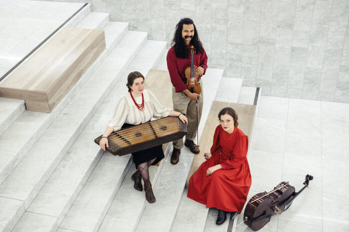 Kapela Kotra Drei jüdische Musiker mit ihren Instrumenten auf einer Treppe sitzend und stehend
