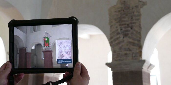 Raum in einer Abteikirche mit einem Tablet mit Augmented Realitiy-Darstellung der Stuckfiguren