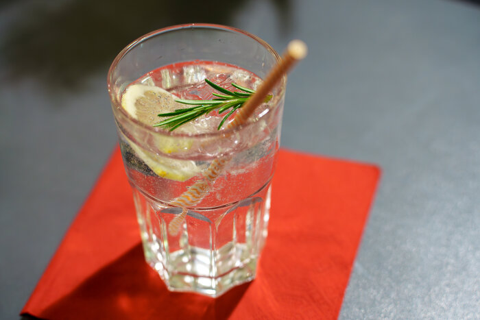 Motiv „Alles koscher“ Ein großes Glas mit Gin inkl. Zitrone und Strohhalm auf einer roten Serviette