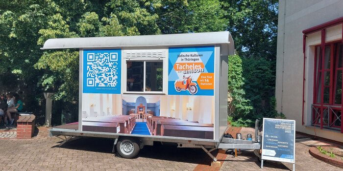 Ein bedruckter Bauwagen, darauf die Innenansicht einer Synagoge