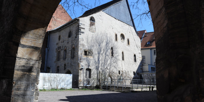 Die Alte Synagoge von der Waagegasse aus gesehen. Im Vordergrund des Fotos der steinerne Torbogen, der auf das Nachbargrundstück führt, von der Synagoge sieht man die Nord- und die Westfassade.