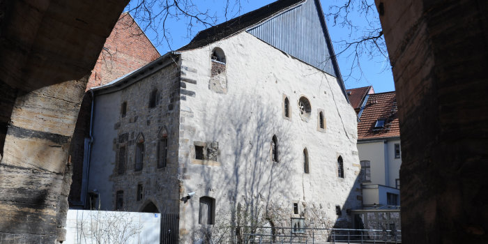 Die Alte Synagoge von der Waagegasse aus gesehen. Im Vordergrund des Fotos der steinerne Torbogen, der auf das Nachbargrundstück führt, von der Synagoge sieht man die Nord- und die Westfassade.