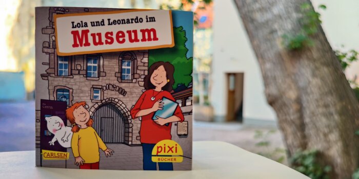 Ein buntes Pixi-Buch mit dem Gebäude der Alten Synagoge Erfurt im Hintergrund