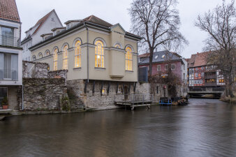 ein Haus mit großen beleuchteten Fenstern an einem Flussufer