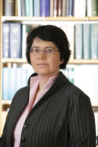 Eine Frau mit kurzen dunklen Haaren und einer randlosen Brille blickt in die Kamera.