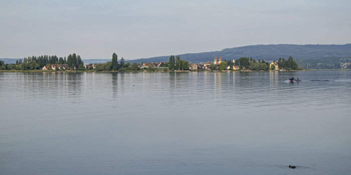 Eine Insel mit Bäumen und Gebäuden inmitten einer Wasserfläche 