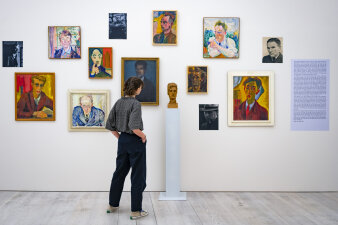 eine Person betrachtet Gemälde in einer Ausstellung
