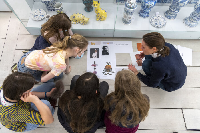 Kunstpädagogischer Workshop mit Kindern im Angermuseum Von oben fotografierte Personen die auf dem Boden hocken und auf einen Zettel mit Bildern schauen