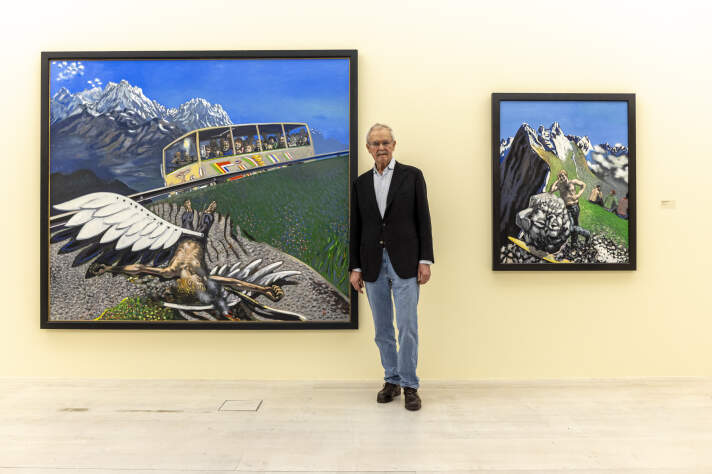 ein Mann steht neben zwei großen bunten Gemälden
