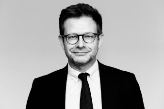 Schwarz-Weiß-Porträt eines Mannes mit Brille, Krawatte und Anzug