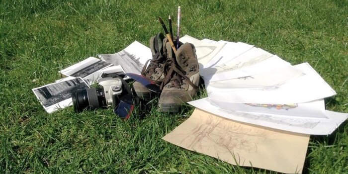 Eine grüße Wiese mit darauf liegenden Schuhen, Zetteln und einer Kamera