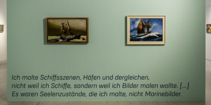 mehrere Gemälde hängen an hellgrünen und weißen Wänden