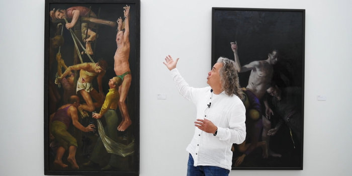 Foto: Online-Kunstpause: Rundgang durch die Sonderausstellung „Volker Stelzmann. Stadt – Werkstatt“ © Stadtverwaltung Erfurt / Lutz Edelhoff ein Mann erklärt ein Bild in einer Ausstellung