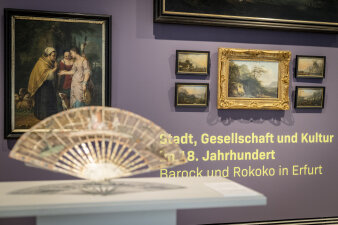 im Vordergrund ein Fächer, im Hintergrund eine Wand mit Gemälden und Schriftzug "Barock und Rokoko in Erfurt"