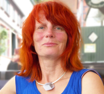 Portrait einer Frau mit roten Haaren und blauem Oberteil
