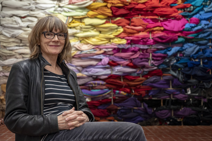 Bauhausfrau: Liz Bachhuber vor ihrer Installation in der Kunsthalle Eine Dame sitzt vor einer Wand aus bunten Kleiderresten