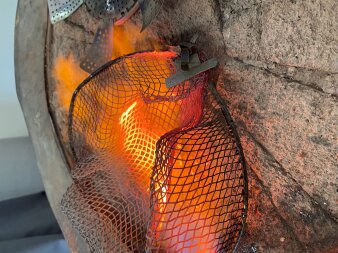 Metallkorb in einer heißen orangefarbenen Flamme