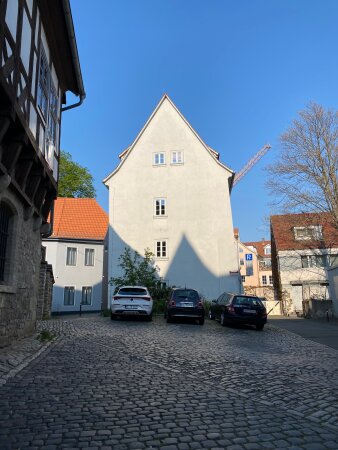 Blick auf ein helles Gebäude mit Kopfsteinpflaster im Vordergrund