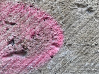 Blick auf einen rosa Farbfleck auf einer Steinwand