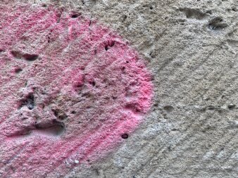 Blick auf einen rosa Farbfleck auf einer Steinwand