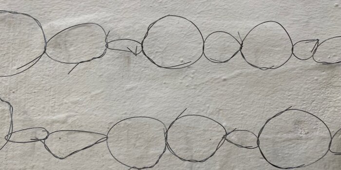 Foto: Linien © Sarah Ordoñez Weiße Wand mit verschiedenen großen verbundenen Ringen aus Draht